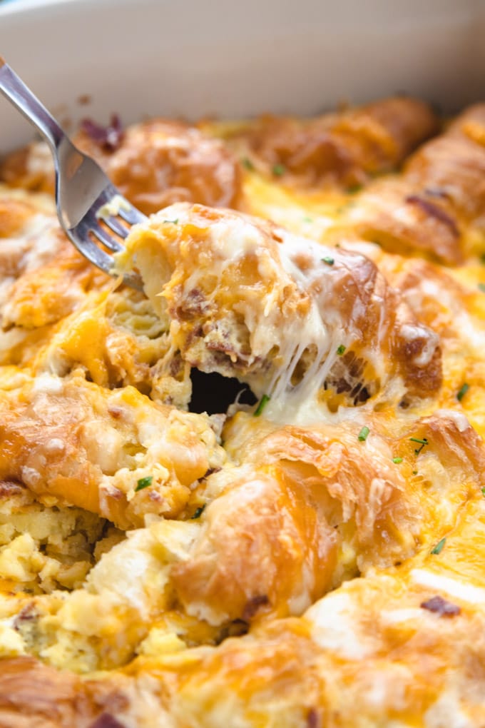 A fork pulling the breakfast casserole with cheese.