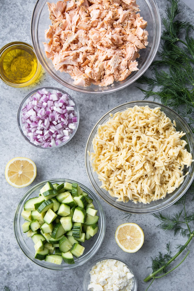 bowls of ingredients for salad with herbs around it.