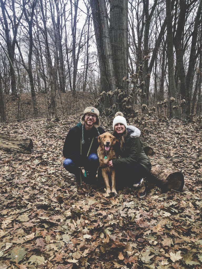 Two people in the woods with their dog.