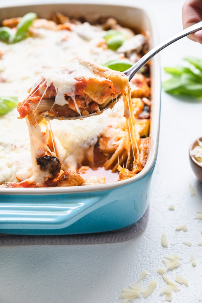 A scoop of pasta bake being pulled out of a casserole dish.