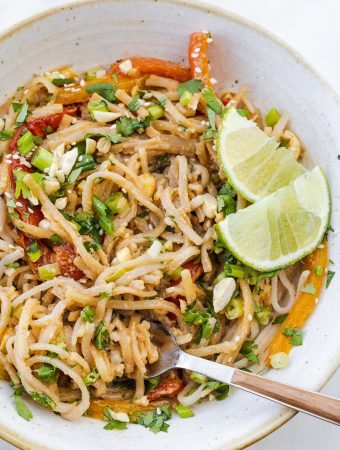 a bowl of noodles with peanut sauce and a fork