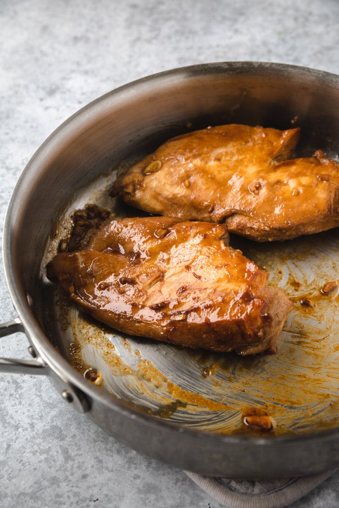 Chicken teriyaki cooking in sauce in a pan.