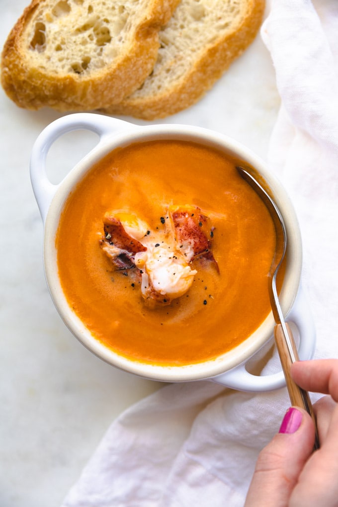 A spoon in soup with a towel next to it.