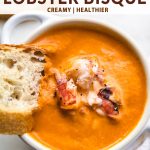 a bowl of bisque with bread and lobster.