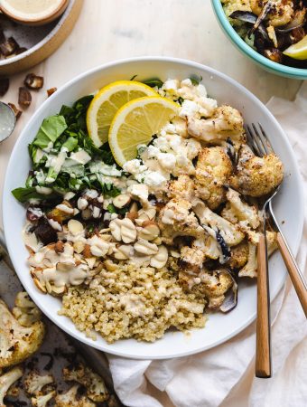 Mediterranean cauliflower salad in a bowl with a fork and dressing.