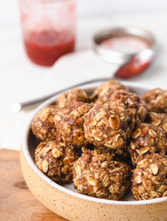 peanut butter and jelly bites in a bowl with jelly behind it.