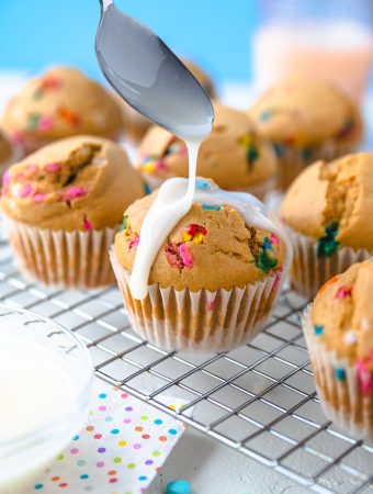 a funfetti cupcake with glaze being drizzled on it.