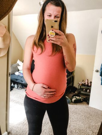 Me holding my pregnant belly in a pink top.