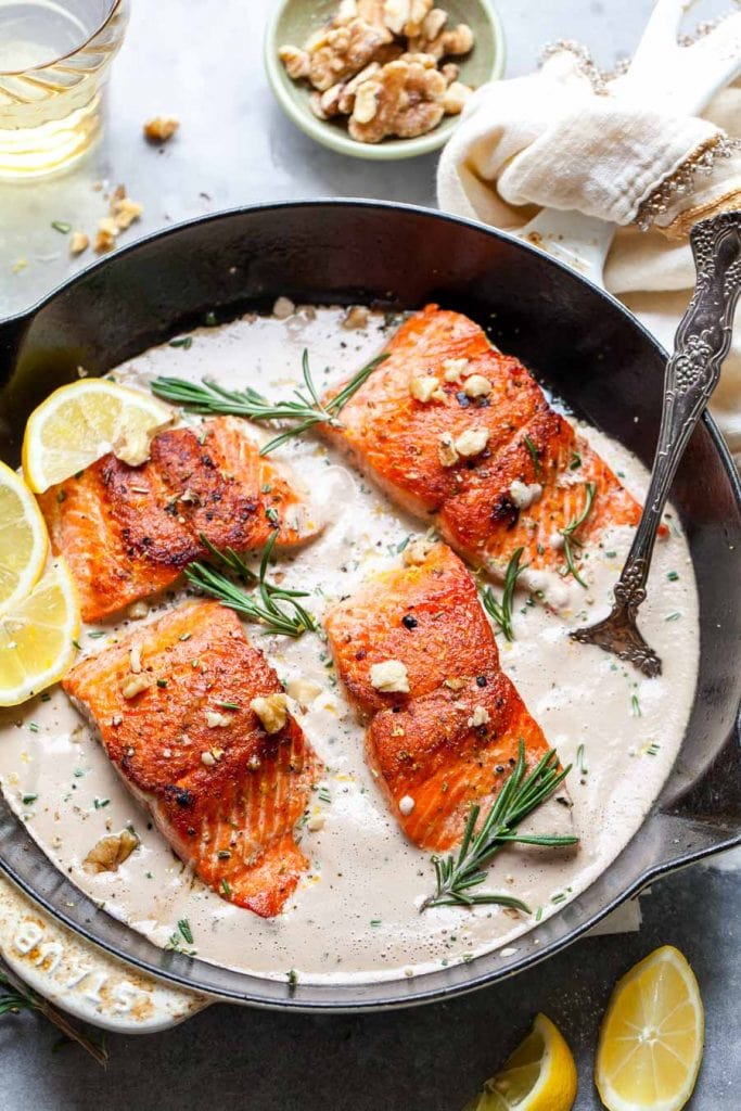 Salmon in a cast iron skillet with lemons.