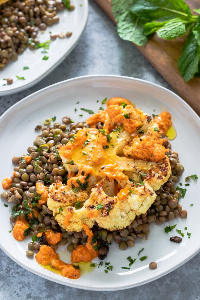 Cauliflower steak over a bed of lentils on a plate.