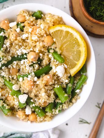 A bowl of green bean quinoa salad with a lemon wedge