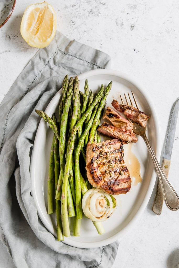 lamb and asparagus on a plate with a fork and knife.