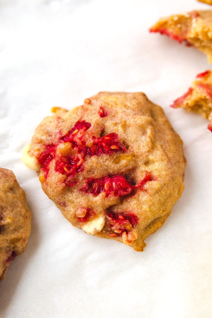 A cookie on a sheet pan with raspberry and white chocolate. 