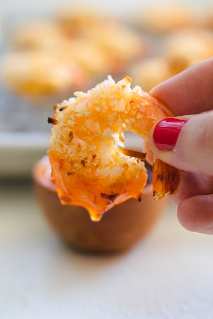 Coconut flakes on shrimp dripping with dipping sauce.