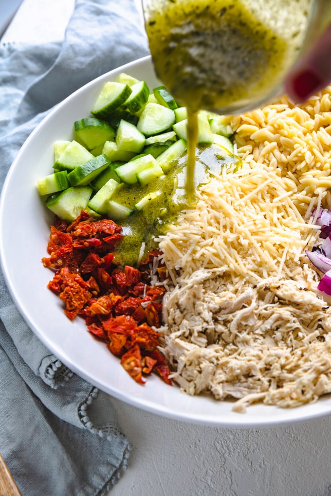 dressing being poured on ingredients in a bowl.