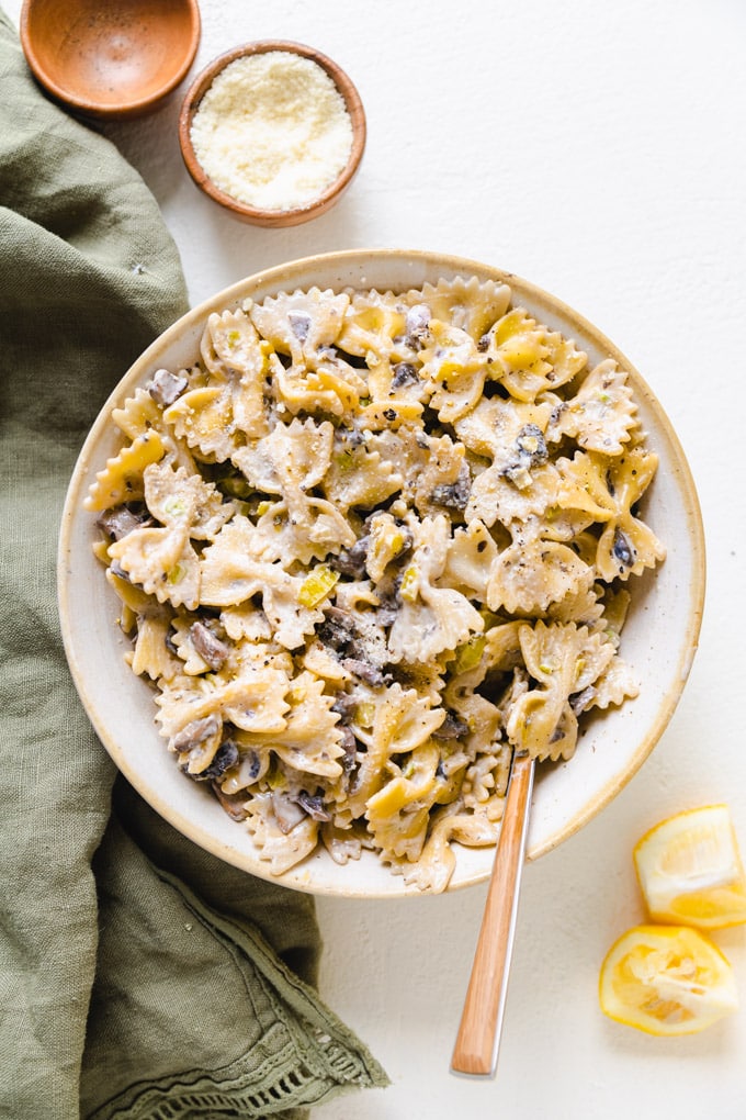 a bowl of pasta with lemon and parmesan next to it.