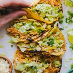 a hand holding a taco with toppings.