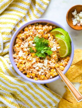 a bowl of Mexican corn dip with lime and cilantro