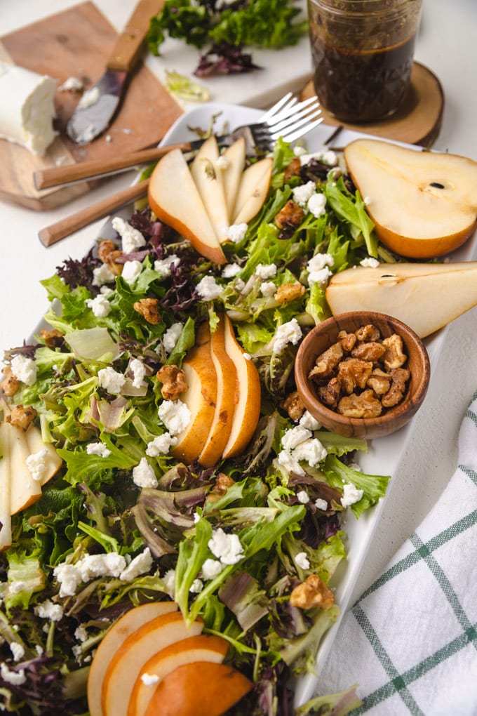 pear salad on a platter with forks and toppings. 