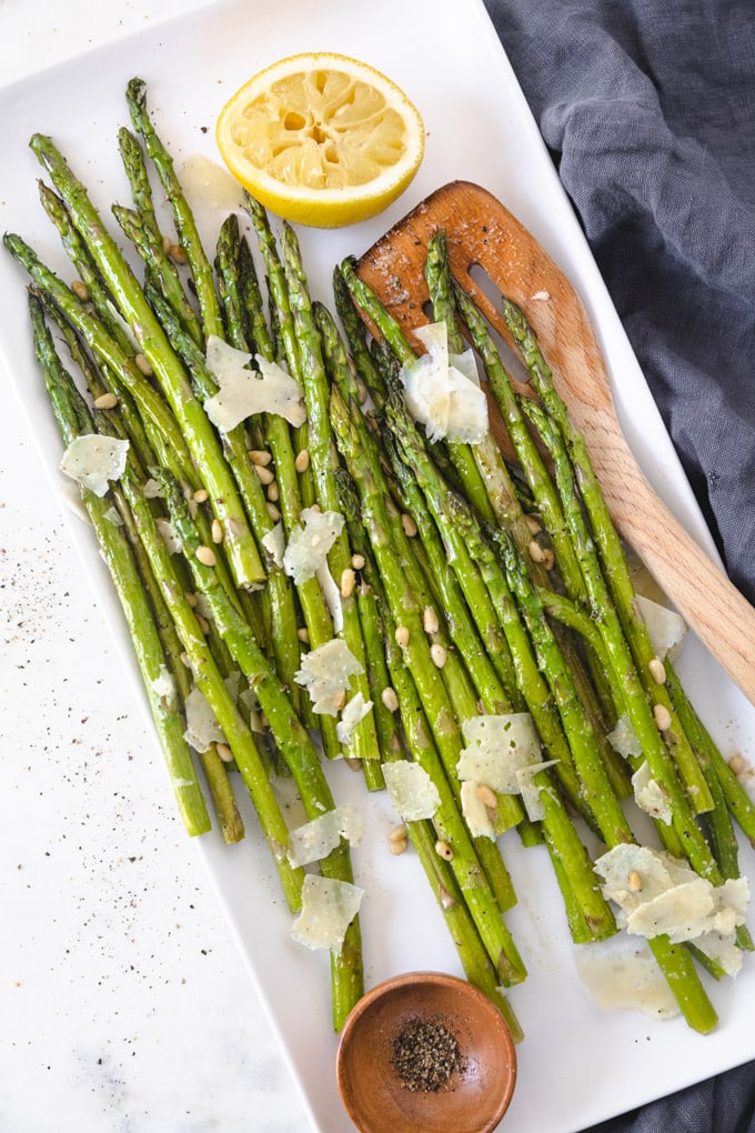 Black pepper and asparagus on a serving tray with a spatula.