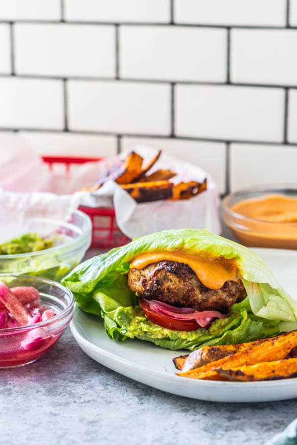 turkey burgers in a lettuce wrap with fries.