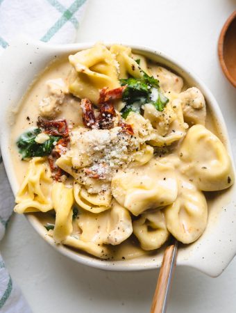 tortellini soup in a bowl with cheese on top.