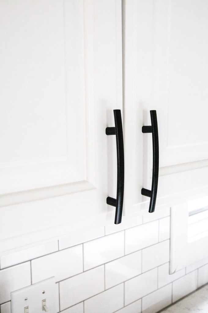 White cabinets with black curved handles hardware.