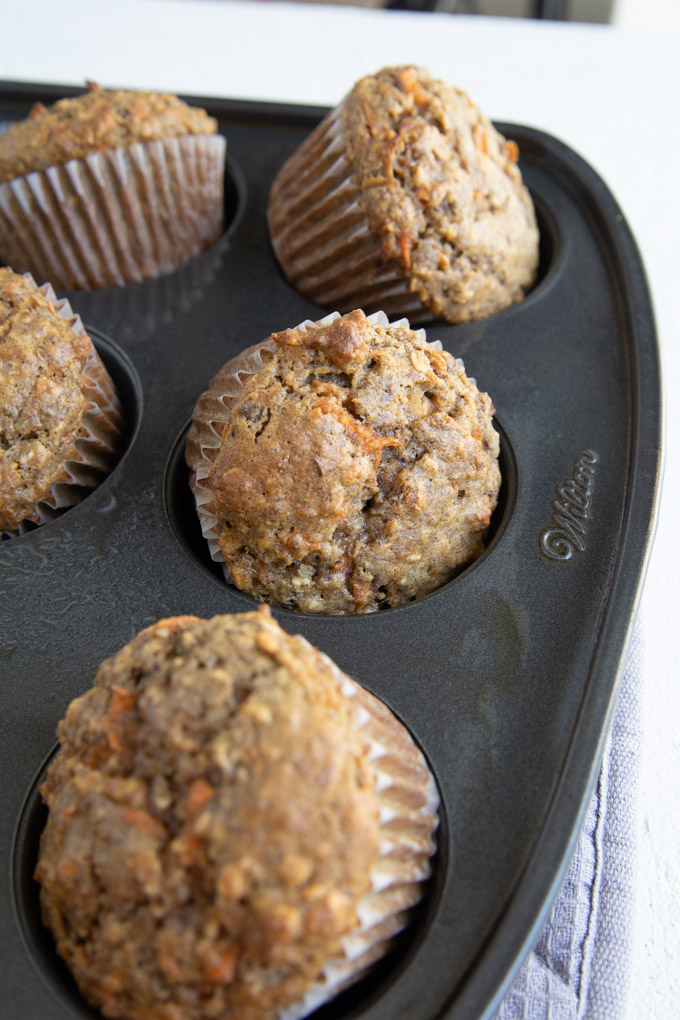 multiple muffins popping out of the muffin tin with liners. 