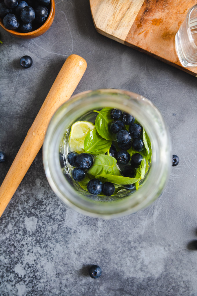 A top down video of ingredients for basil blueberry cocktail. 