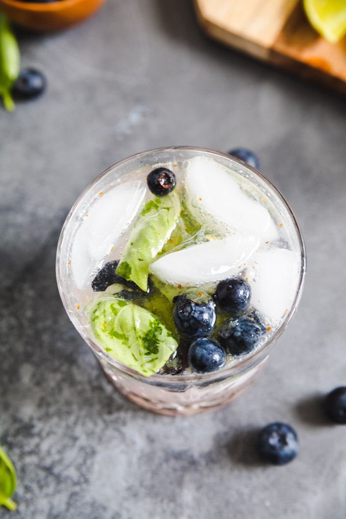 basil leaves and blueberries floating on ice cubes. 