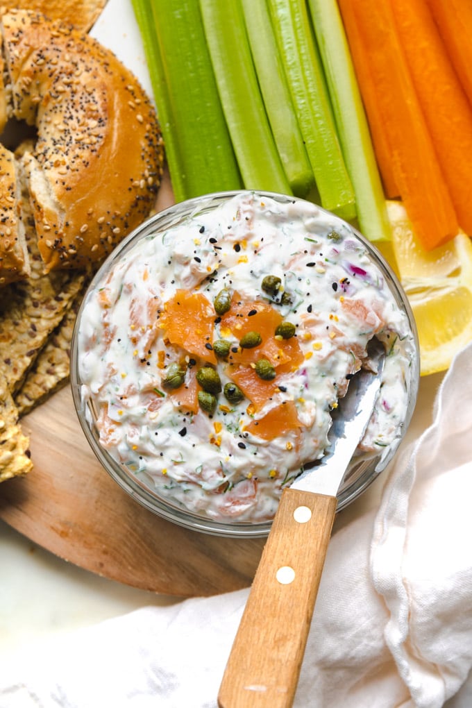 a bowl with dip in it and veggies and bread around it. 