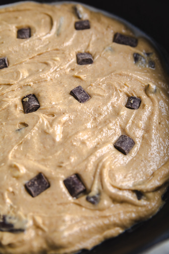 S'mores dough in a cast iron skillet with chocolate chunks on top. 