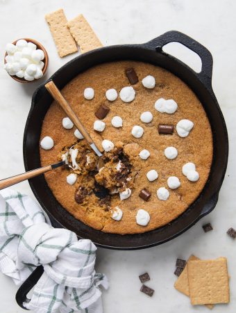 cast iron skillet with marshmallows and chocolate around it.