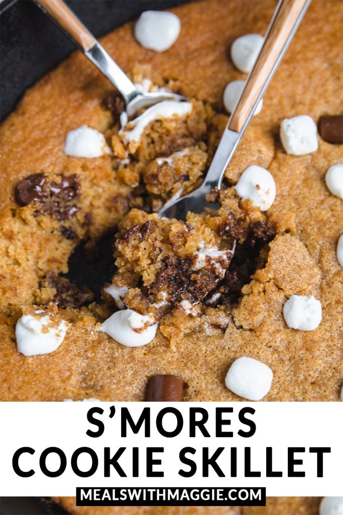 Two spoons in the  s'mores cookie skillet with melted chocolate and marshmallows.  