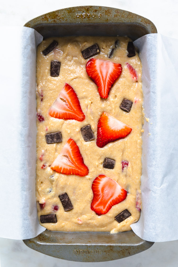 Raw bread batter with strawberries and chocolate chunks on top. 