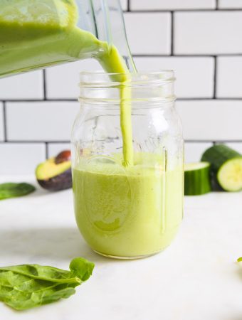 a mason jar being poured with a green smoothie.