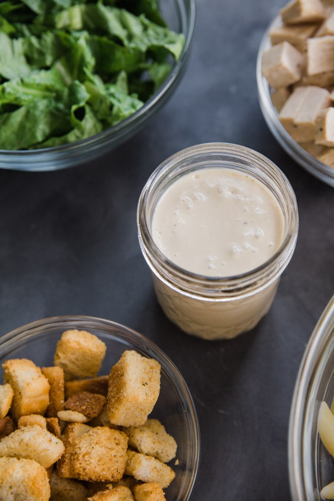 salad dressing in a mason jar next to bowl.