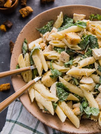 chicken caesar pasta salad in a bowl with forks.