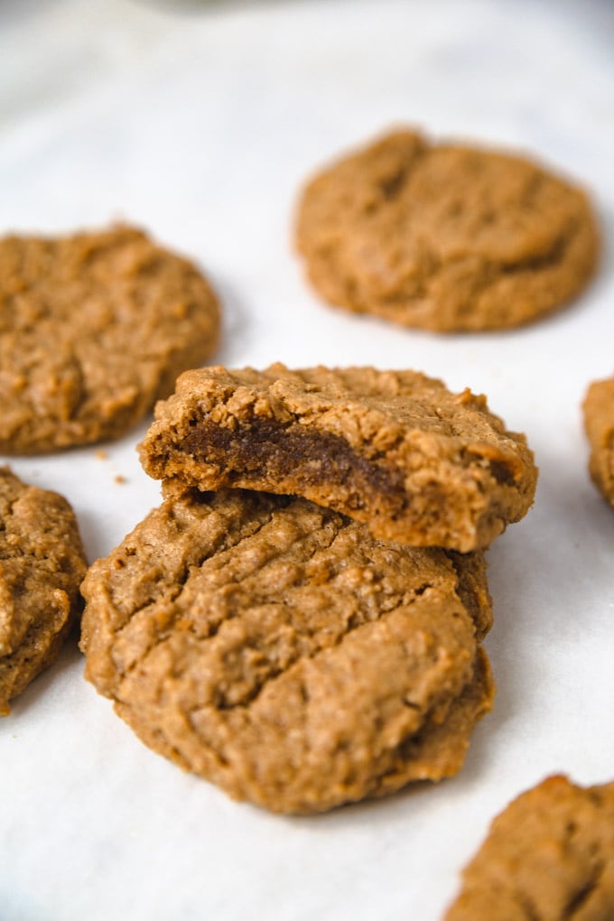 a peanut butter cookie on a sheet pan with a bite taken out of it.