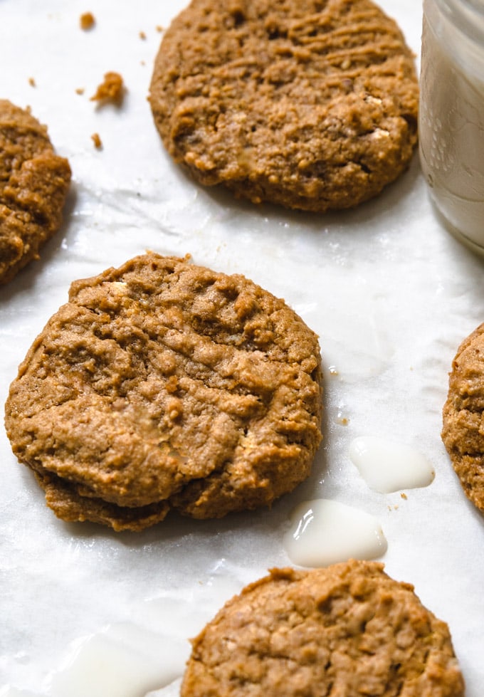 a peanut butter cookie up close with a glass on milk