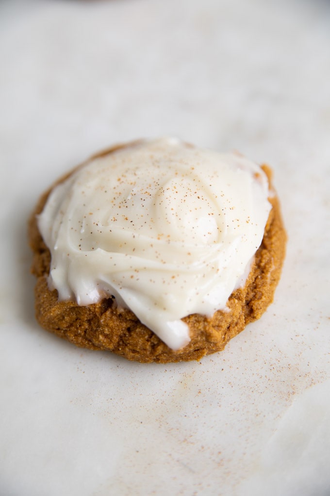 one cookie with cinnamon sprinkled on top of cream cheese frosting.