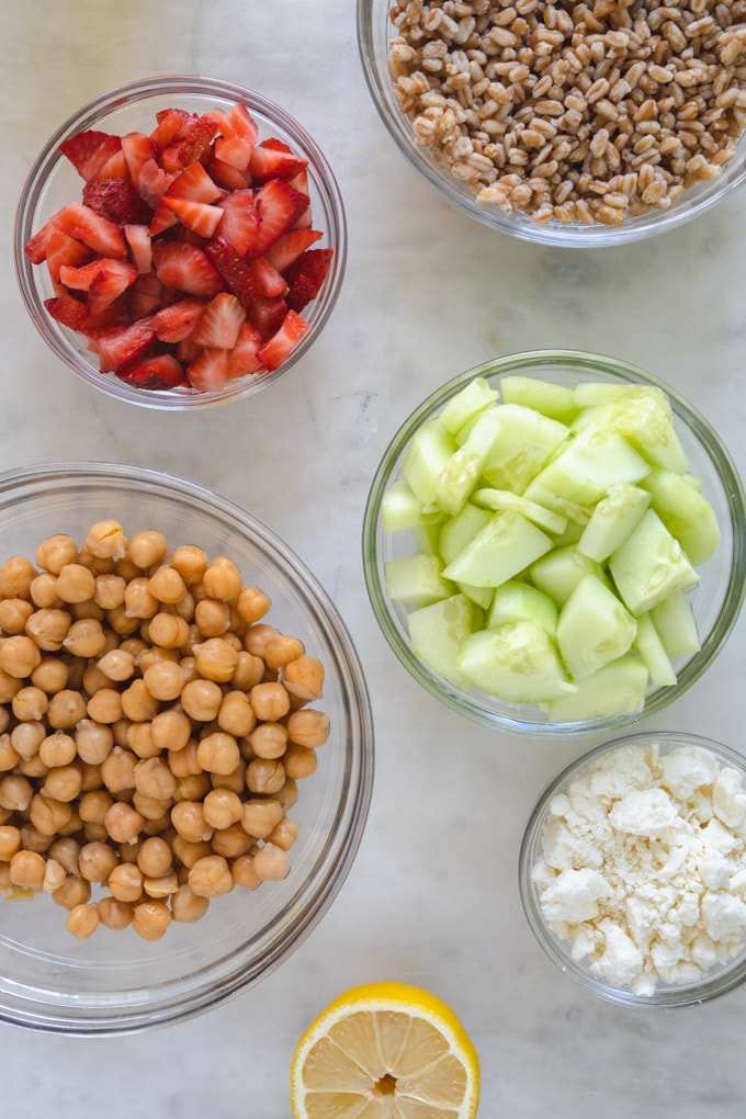 separate bowls of farro, cucumber, strawberries and chickpeas. 