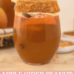 a glass full of apple cider and peanut butter on the rim.