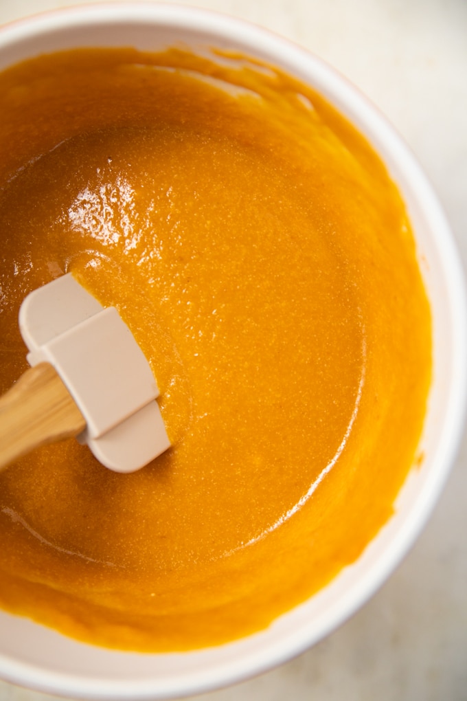 orange pumpkin batter in a bowl with a spatula.