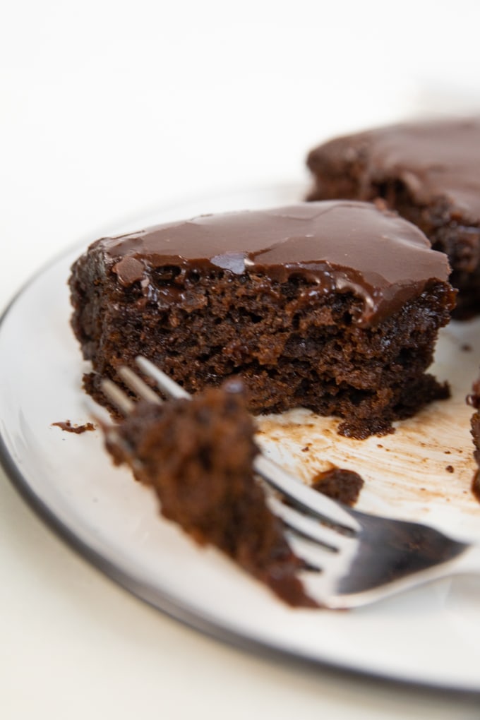 a fork taking a piece of brownie with frosting on top.