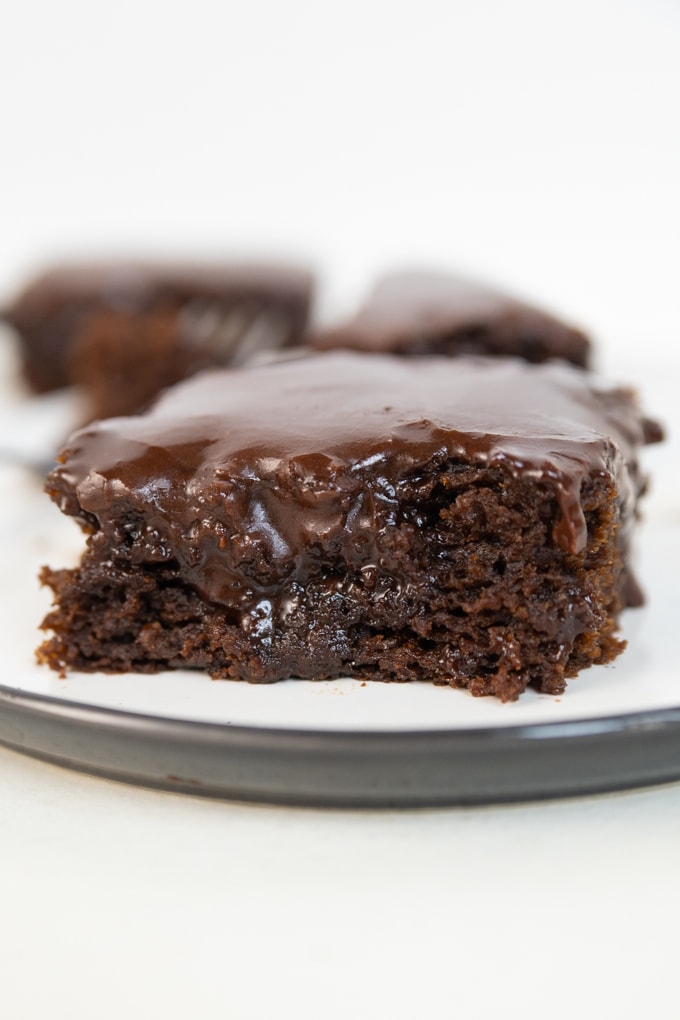 a chocolate brownie on a plate with frosting on top. 