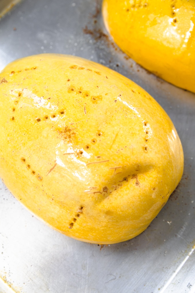 spaghetti squash with fork holes on a sheet pan. 