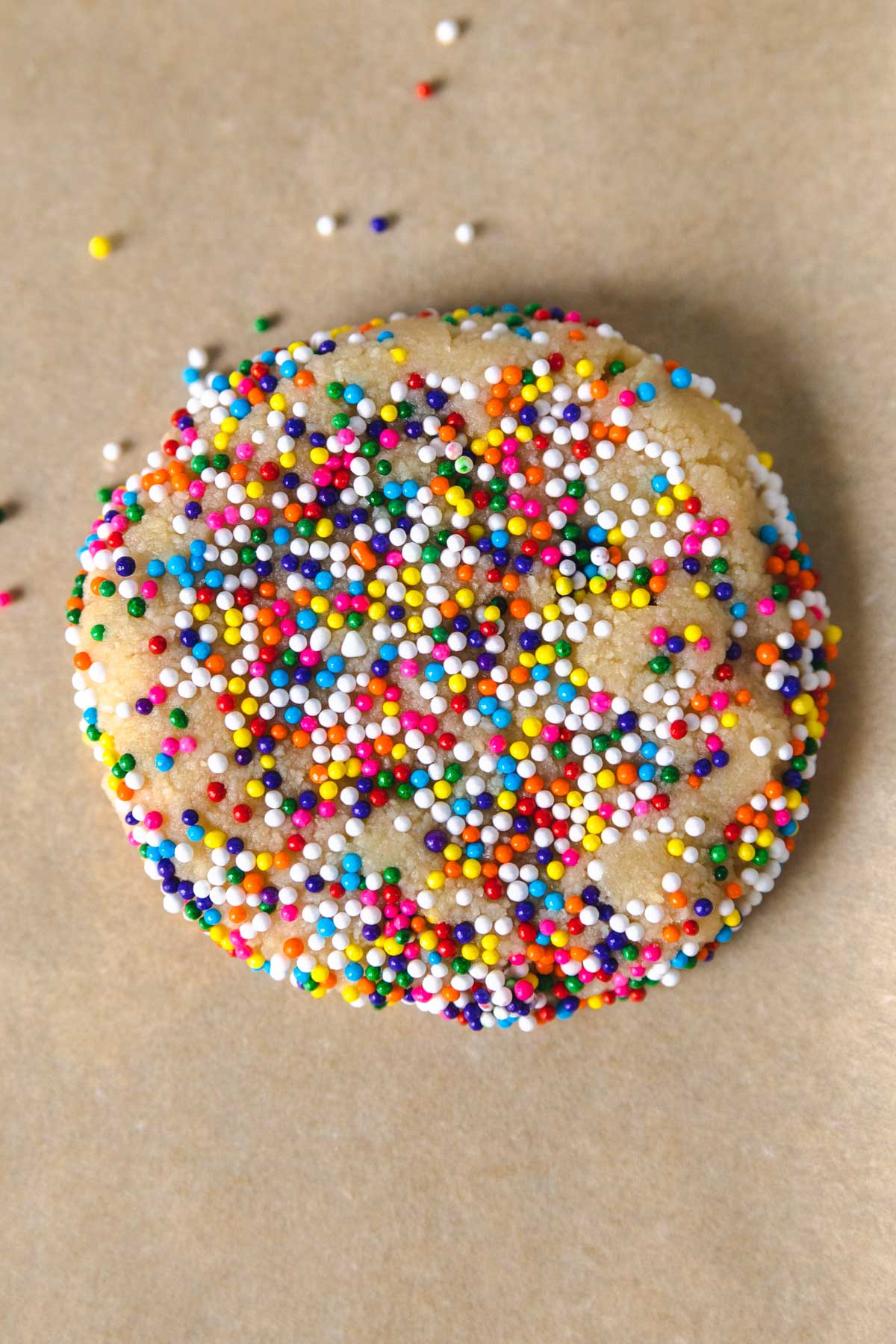 a cookie with sprinkles pressed around the sides and edges on a sheet pan.