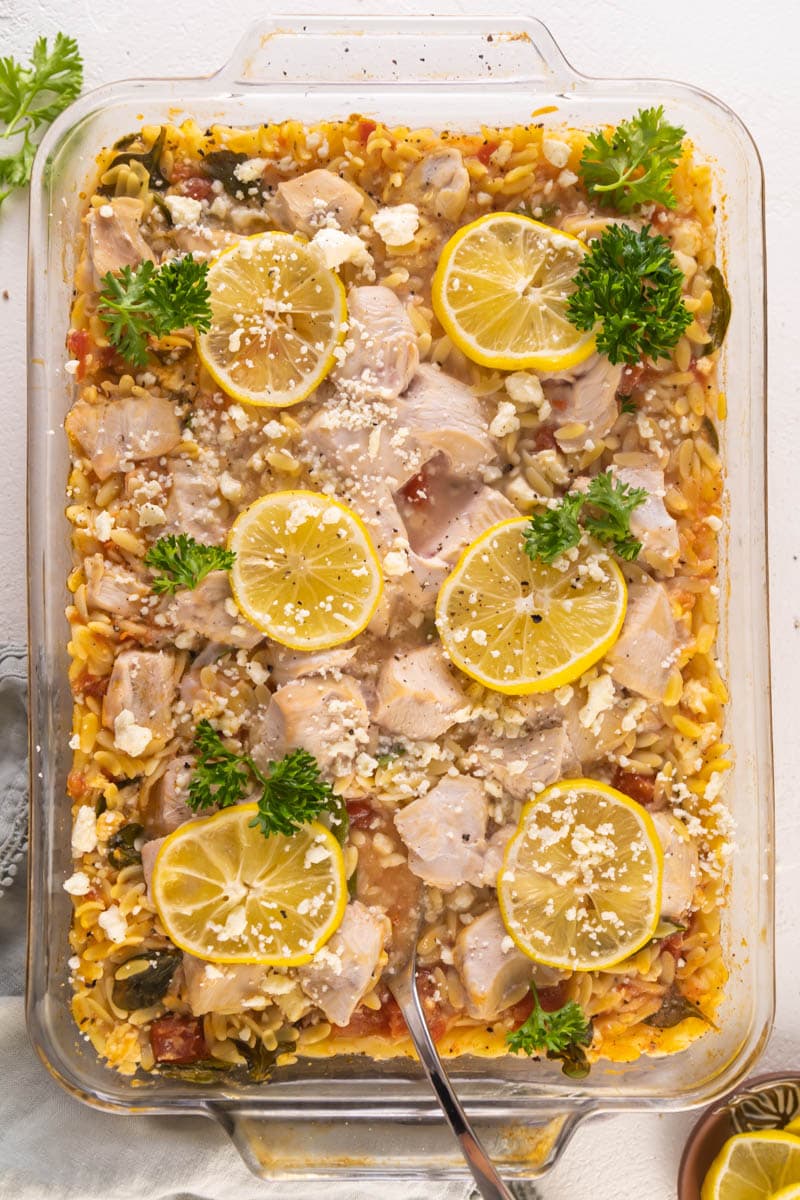 overhead shot of the greek chicken casserole with parsley and lemon on top with crumbled feta. 