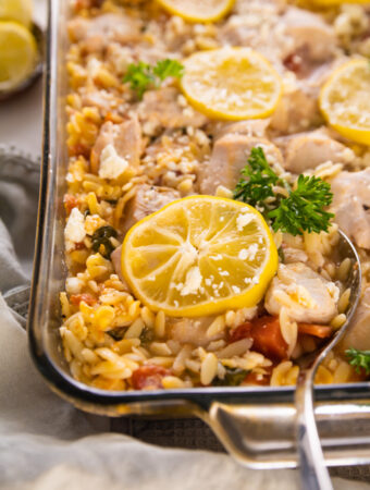 a casserole dish with a spoon serving lemon and chicken.